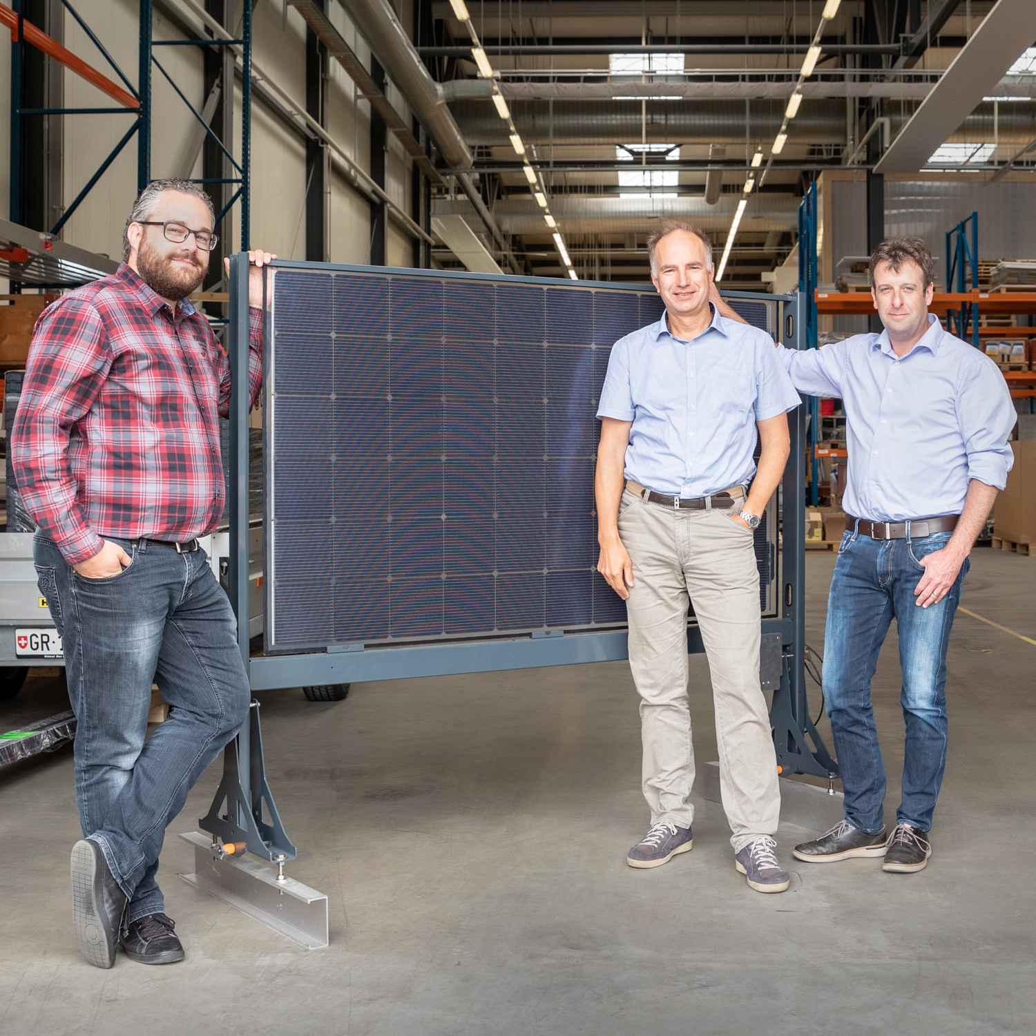 Tamás Szacsvay, Andreas Hügli und Sandro Spescha stehen vor der Lagerhalle, im Hintergrund steht eine Solarzelle