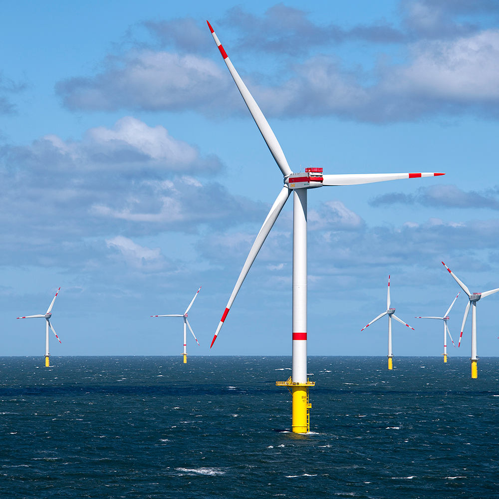 Sechs Windräder im Wasser auf offener See.