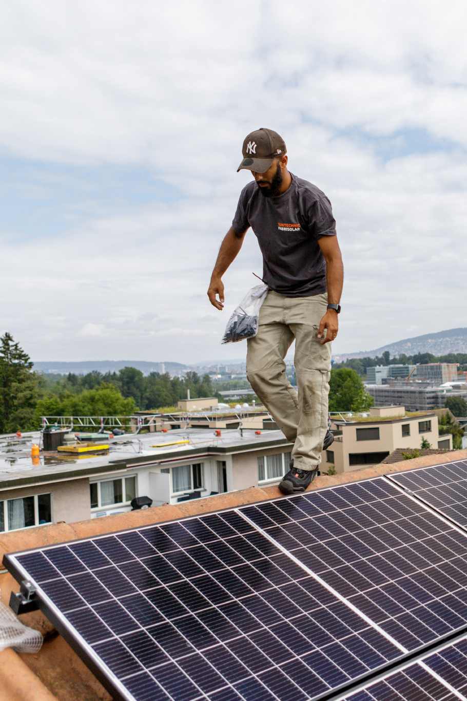 Ein Handwerker läuft über ein Dach, das mit einer Solaranlage bestückt ist.
