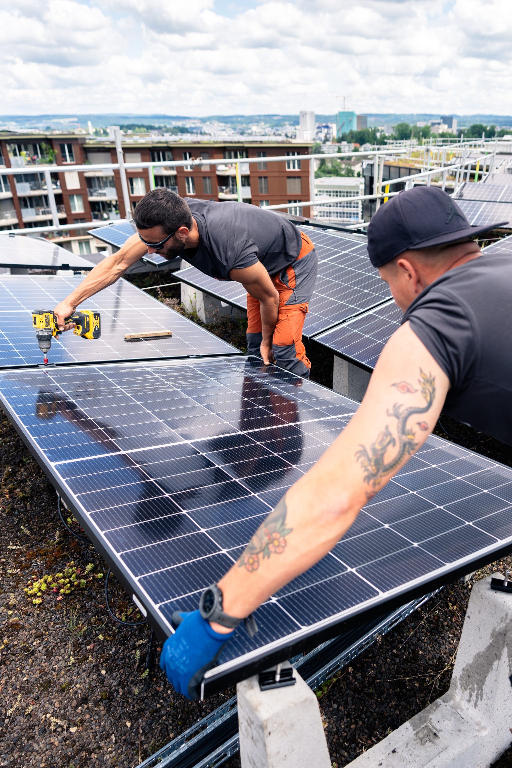 Arbeiter montieren Solaranlagen auf der Überbauung Guggach in Zürich.