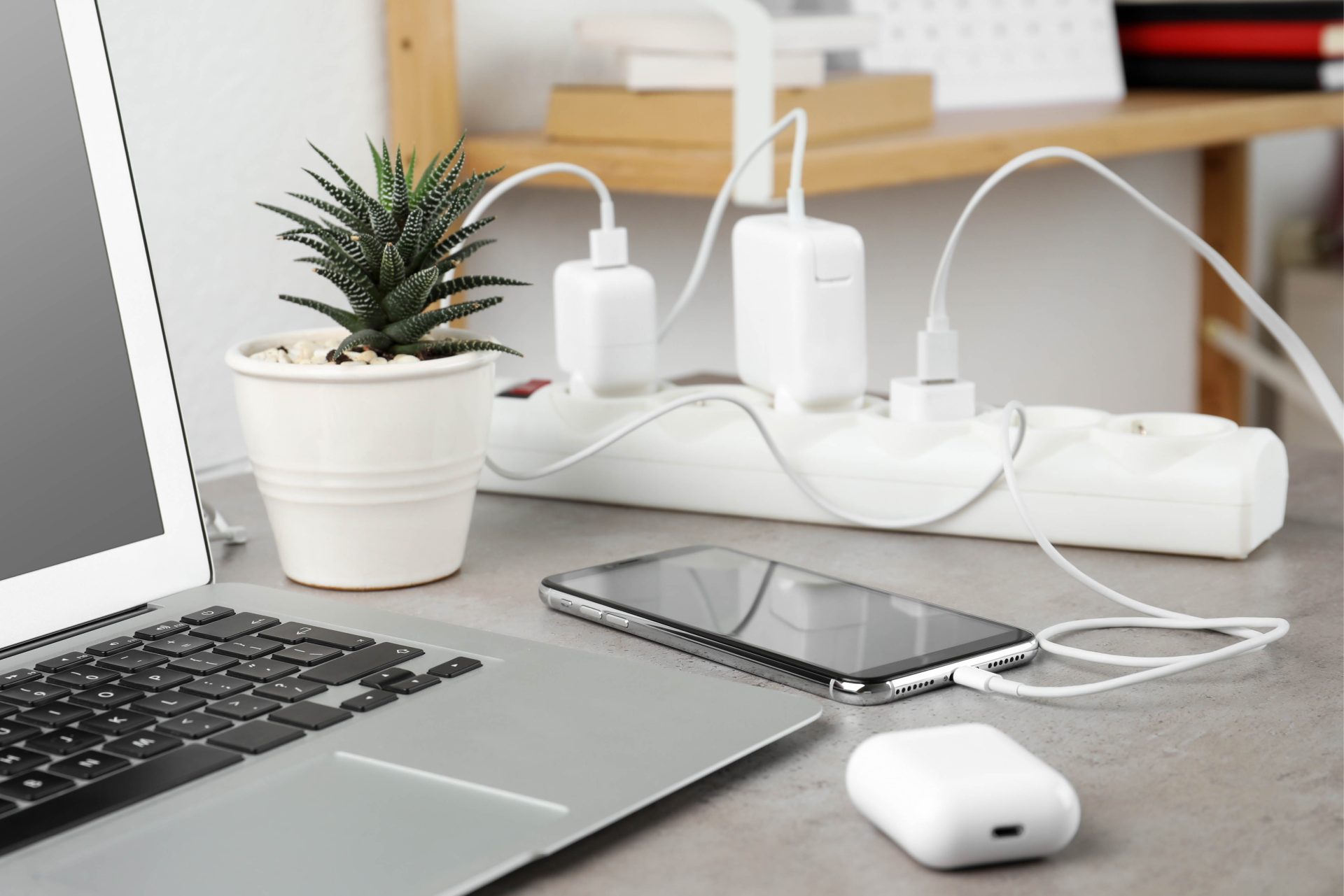 Smartphone-Ladung an Steckerleiste mit Kabel auf einem hellen Stein-Tisch