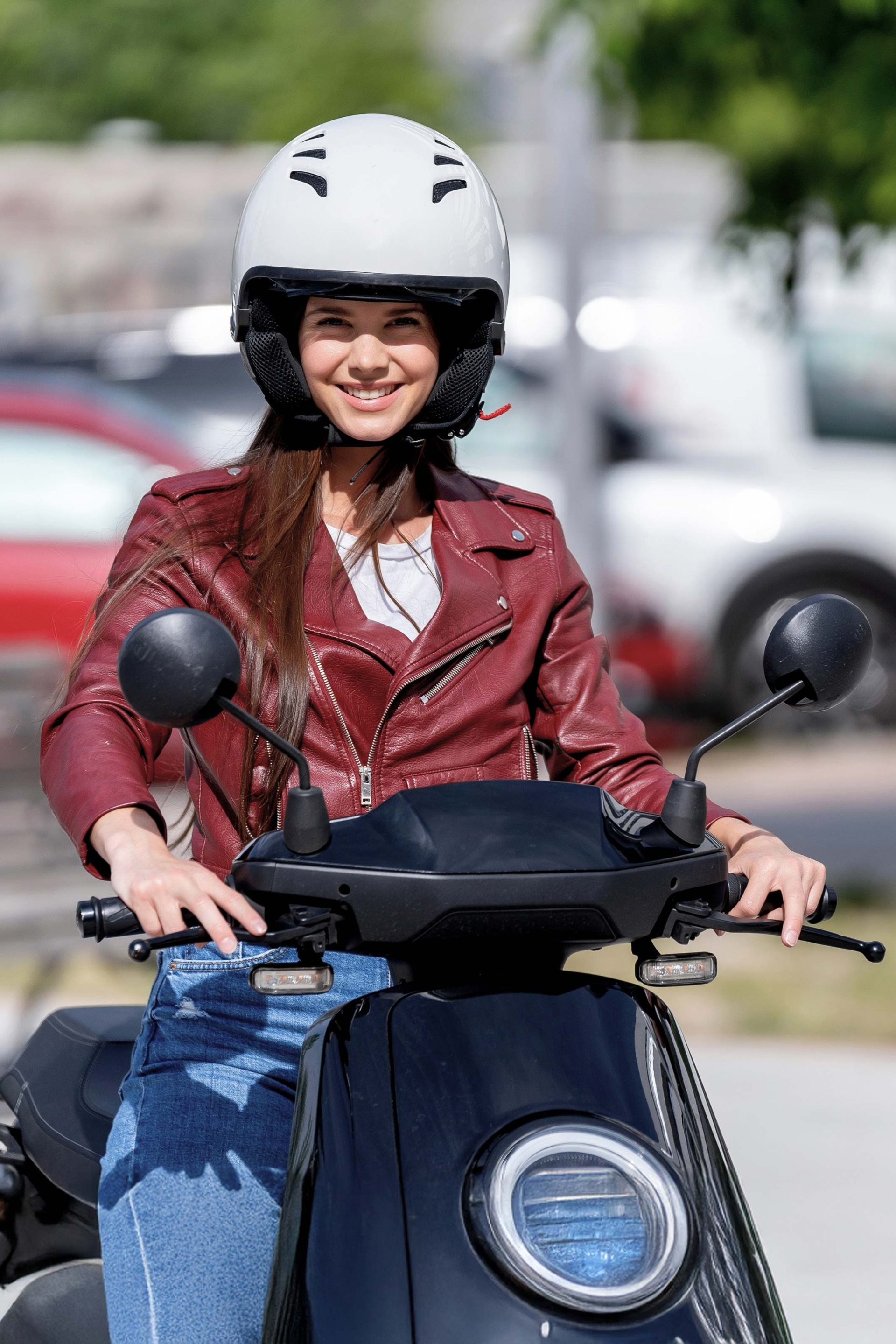 Junge Frau auf einem E-Roller mit Schutzhelm – sicheres und stylisches Elektrofahrzeug für Jugendliche ab 14 Jahren in der Schweiz. Der moderne E-Roller eignet sich ideal als umweltfreundliche Alternative zu E-Auto, E-Mofa oder E-Scooter und ist besonders beliebt bei Jugendlichen, die sich für Elektromobilität interessieren.