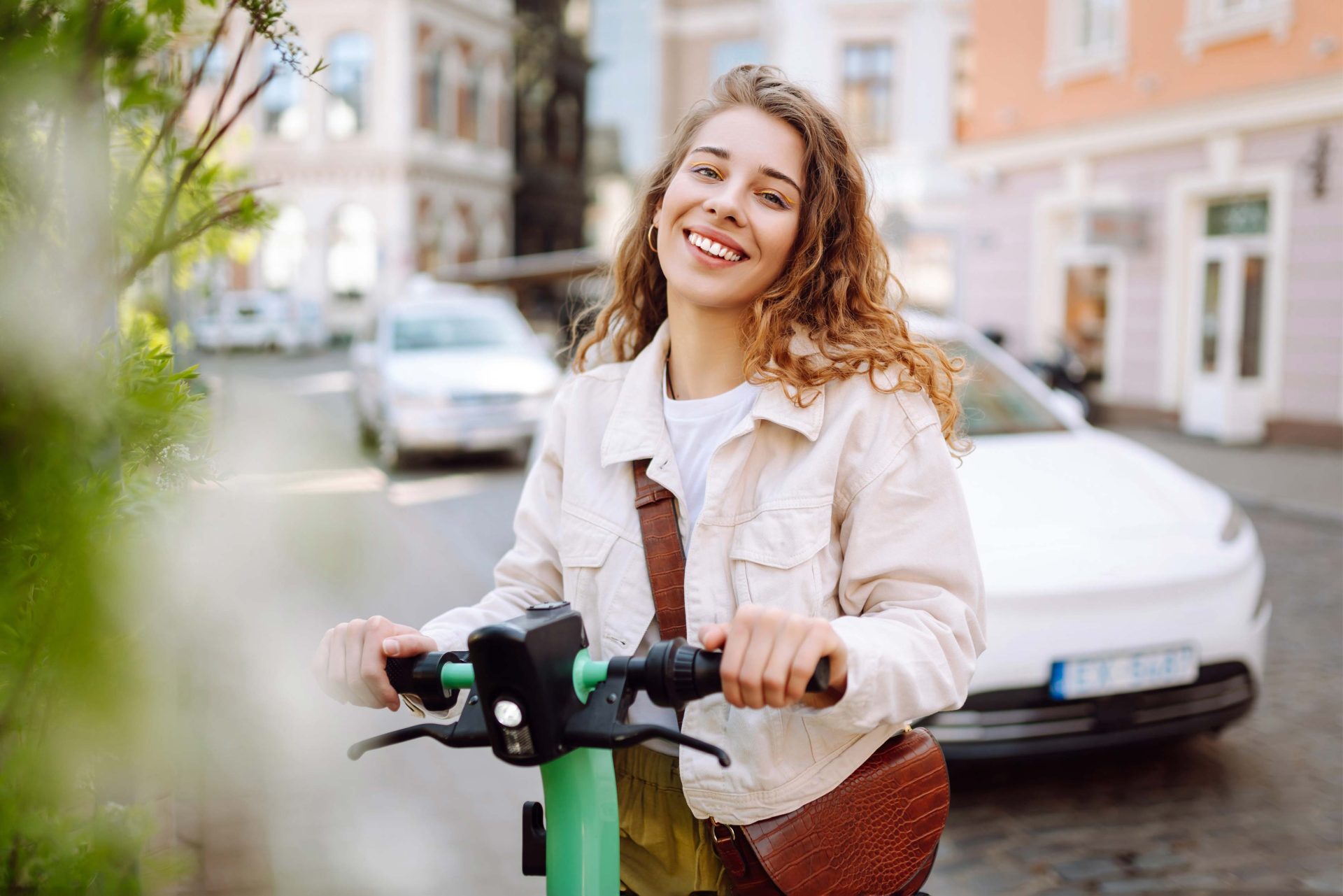Junge Frau mit grünem E-Scooter in der Innenstadt – modernes Elektrofahrzeug für Jugendliche in der Schweiz, ideal für nachhaltige Mobilität ab 14 Jahren. E-Scooter bieten eine attraktive Alternative zu E-Roller, E-Mofa und E-Auto und sind besonders bei jungen Menschen beliebt, die flexibel und umweltbewusst unterwegs sein wollen.