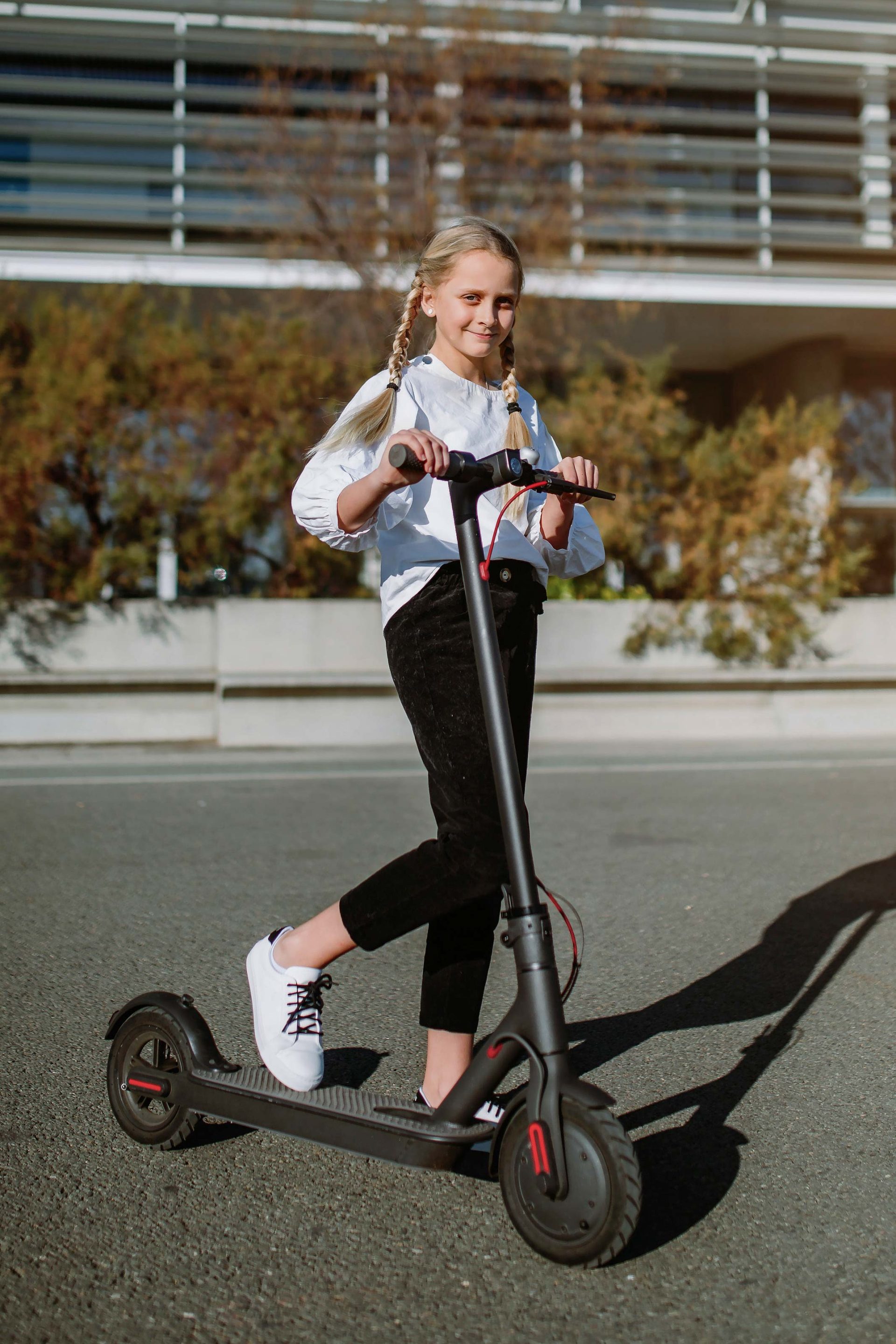 Mädchen mit E-Scooter im Straßenbereich – kindgerechtes Elektrofahrzeug für Jugendliche, ideal zum Einstieg in die Elektromobilität.