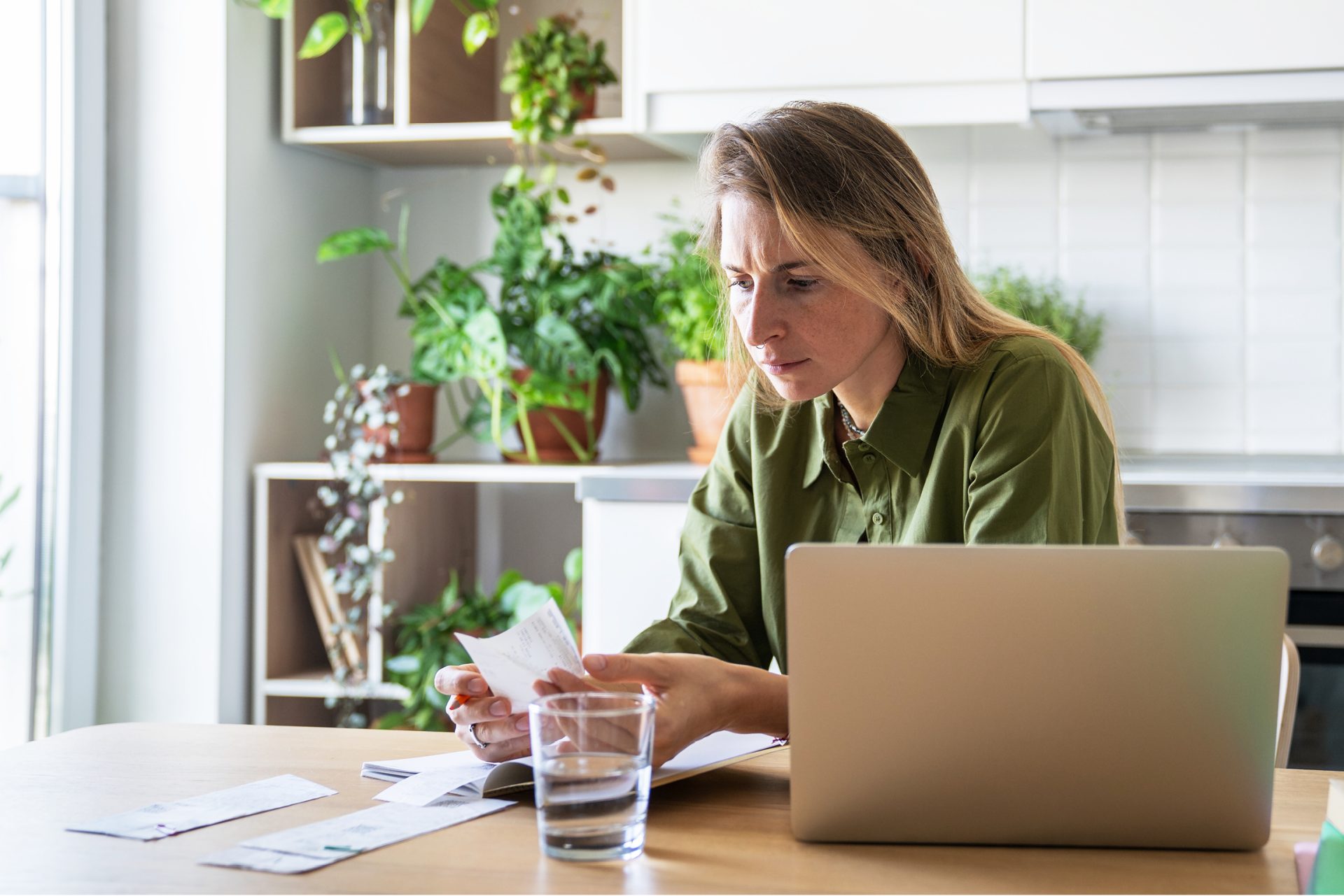 Frau prüft Stromfresser im Haushalt und Stromverbraucher am Laptop, um Energiefresser zu finden.