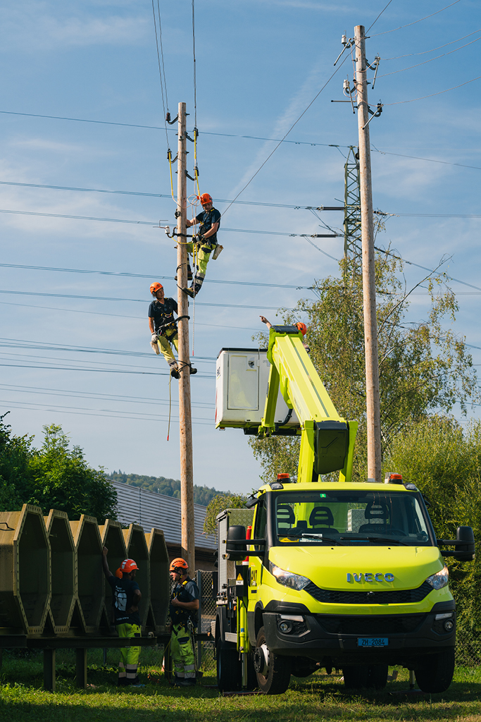 ewz-Mitarbeiter arbeiten mit Hebebühne und Kletterausrüstung an Strommasten in Zürich – zuverlässige Wartung der Stromversorgung Zürich und schnelle Maßnahmen bei Stromausfall.