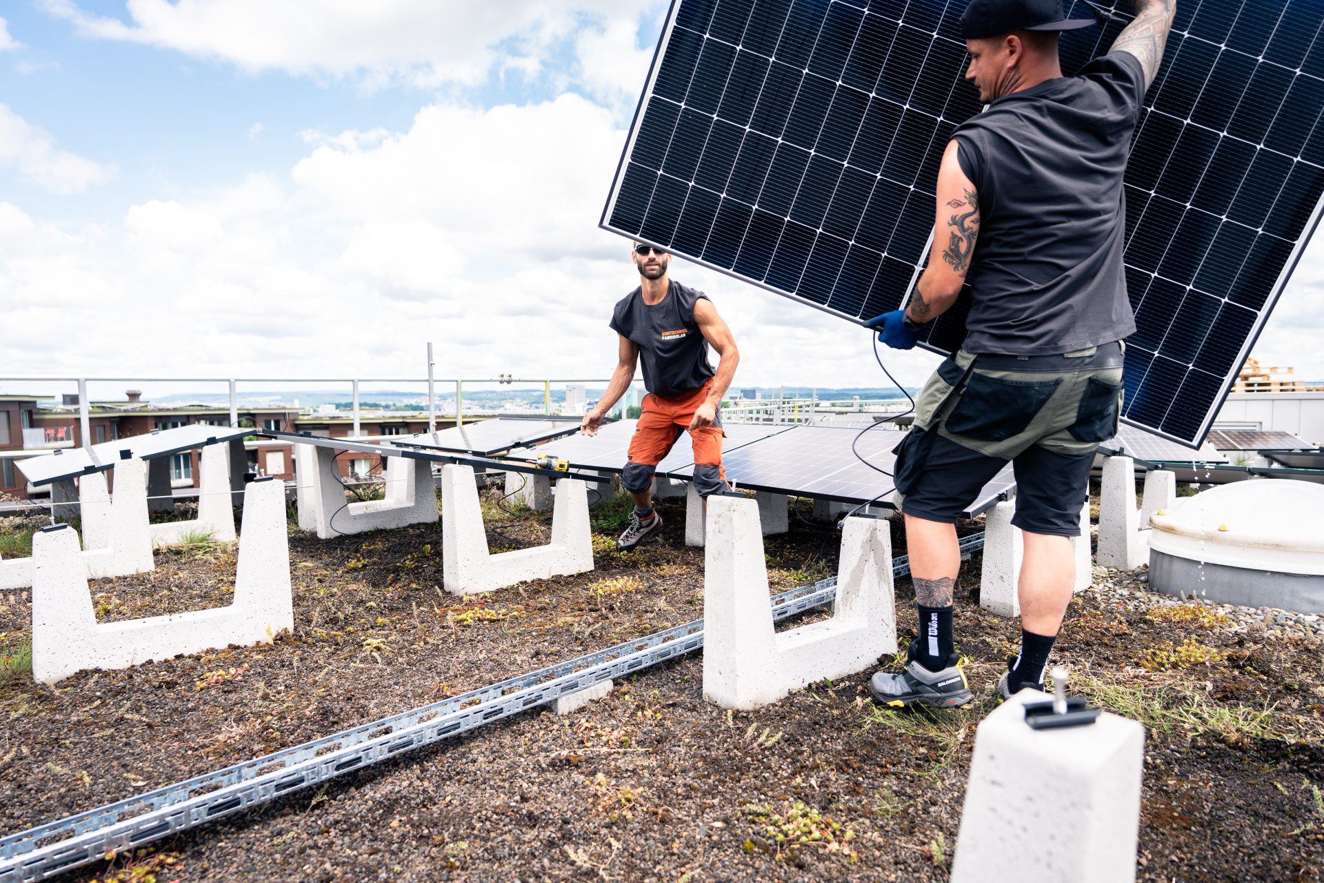 Arbeiter montieren Solaranlagen auf der Überbauung Guggach in Zürich.